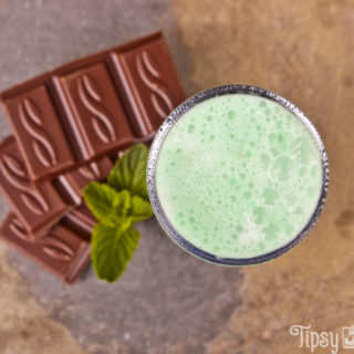 top view of a grasshopper shot with chocolate pieces and mnit leaves on a natural tile background