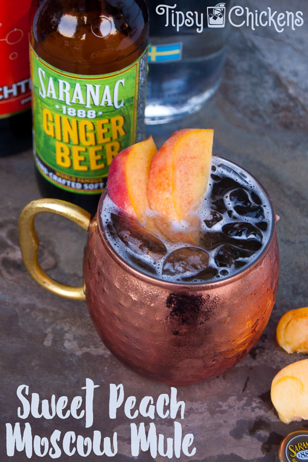 each mocow mule in hammered copper cup with peach slice garnish and saranac ginger beer in the background