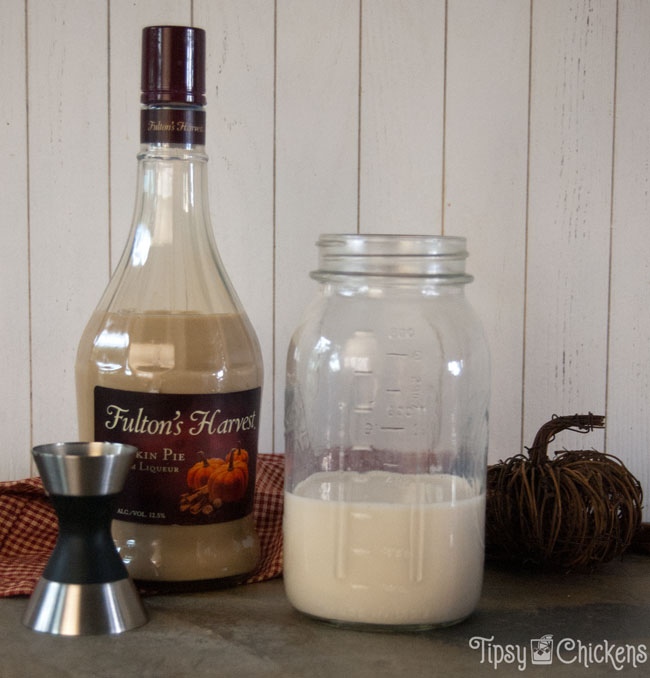 milk and pumpkin pie cream liqueur in a mason jar on a natural tile with a bottle of Fulton's Harvest Pumpkin Pie Cream Liqueur