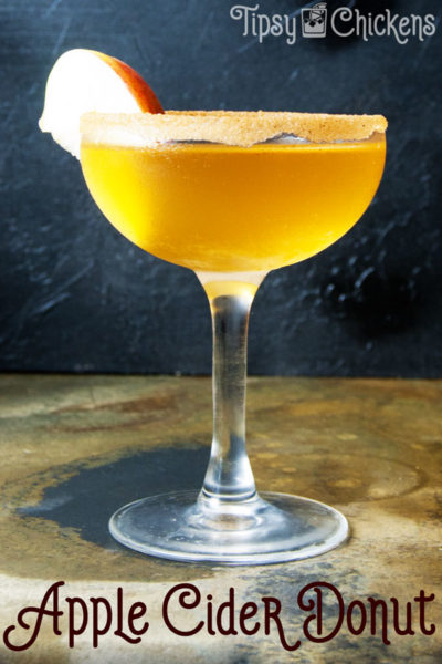 golden apple cider, cake vodka and bitters shaken together into an Apple Cider Donut cocktail served in a frosty coupe glass with a slice of apple