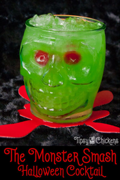 clear skull glass filled with crushed ice, rum, pineapple juice, Midori, blue Curacao with two red maraschino cherries for eyes on a black surface over a red blood splatter coaster