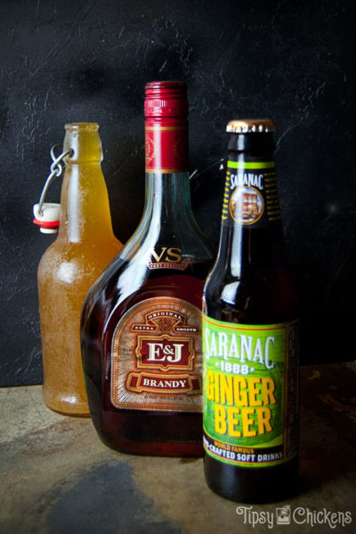 bottle of Saranac root beer, bottle of E&J brandy and flip top bottle apple cider