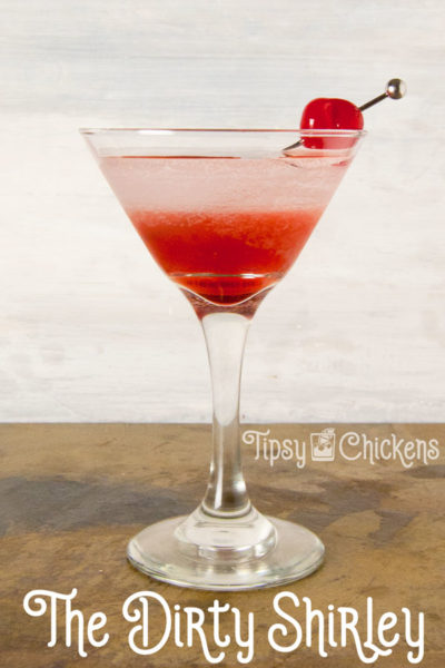 tall martini glass with a dirty Shirley cocktail made with lemon lime soda, lemon vodka and grenadine with a maraschino cherry on a metal pick