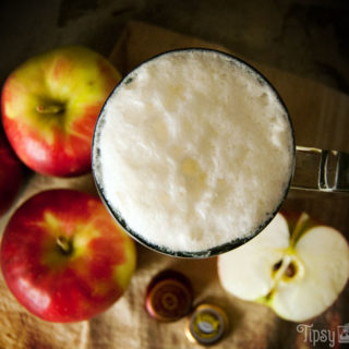 top view of spiked apple cider float made with brandy, apple cider and ginger beer with apples in the background