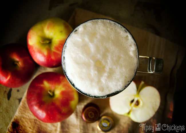 top view of spiked apple cider float made with brandy, apple cider and ginger beer with apples in the background