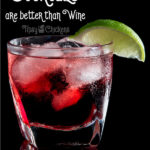 Cranberry and lime cocktail on the rocks in a rocks glass against a black background