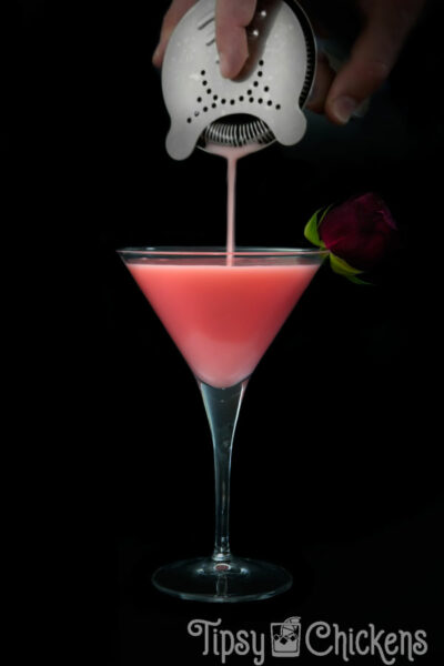 hawthorne strainer straining a pink cocktail into a martini glass
