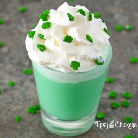 shamrock shot in a small shot glass topped with whipped cram and shamrock sprinkles