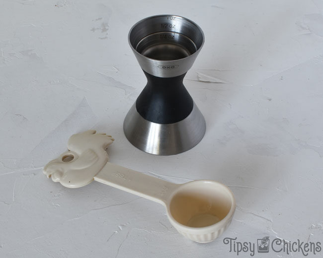 OXO jigger and an off white tablespoon with a chicken on the top